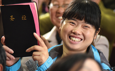 A smiling Chinese woman holding a Bible