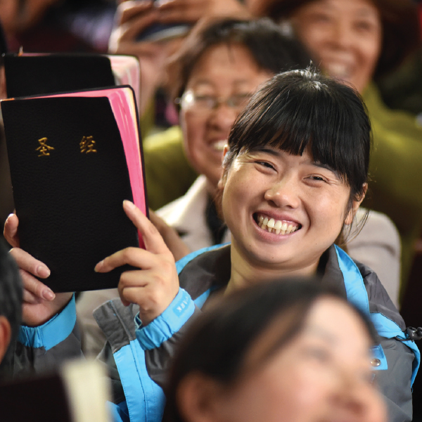 A smiling Chinese woman holding a Bible